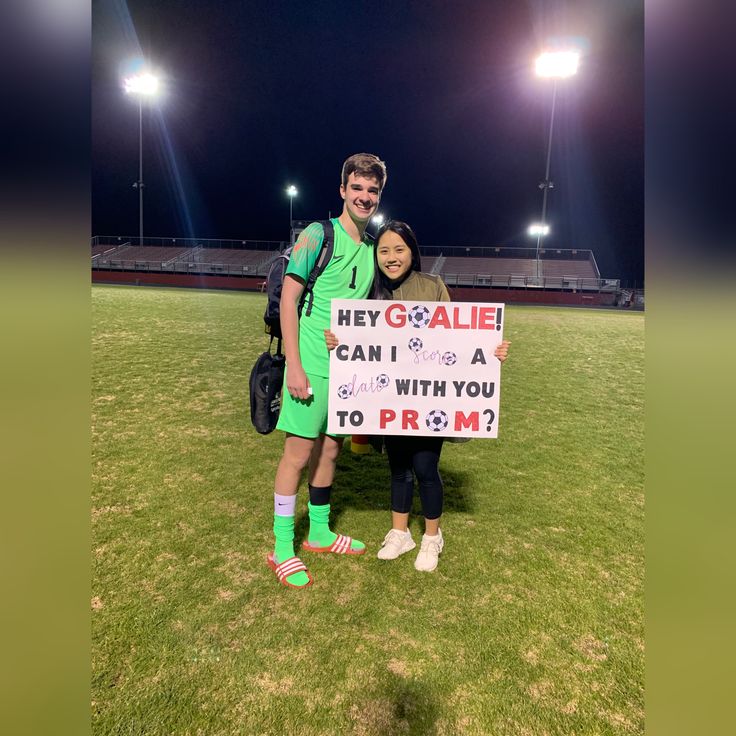 two people standing in the grass with a sign that says hey goalie i can't a deal with you to prom