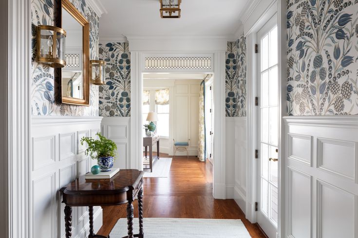 the hallway is decorated with blue and white wallpaper, along with an antique console table