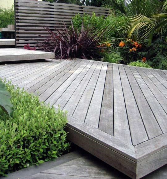 a wooden deck surrounded by plants and trees