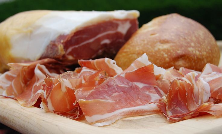 ham and bread on a wooden plate with grass in the background