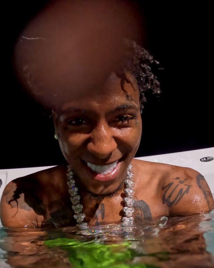 a man in the water with tattoos on his arm and chest, smiling at the camera