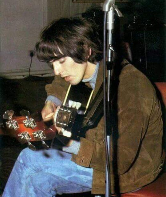 a young man playing an electric guitar in front of a microphone