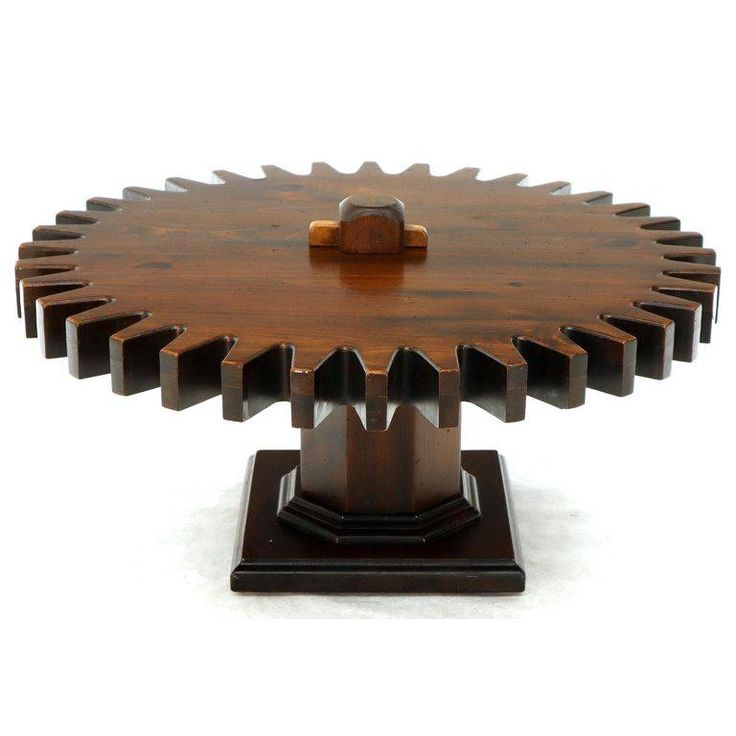 a wooden table topped with metal gears on top of a white surface and brown base