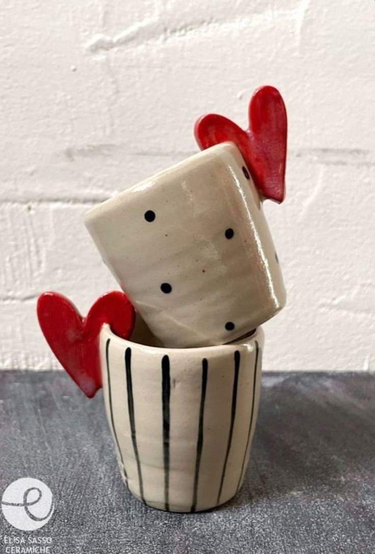 two ceramic cups with hearts in them sitting on a table next to a brick wall