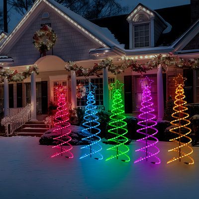 lighted christmas trees in front of a house