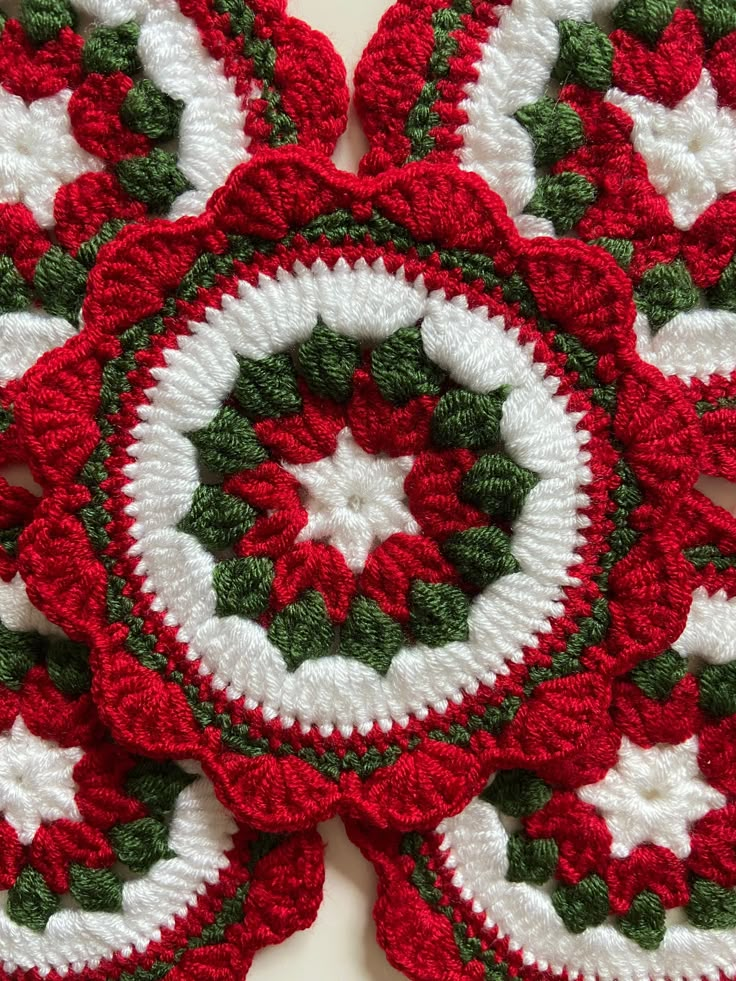 four crocheted coasters with white and green designs on them are arranged in the shape of snowflakes