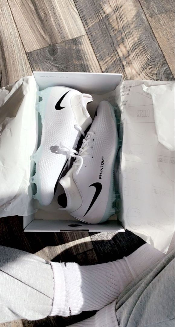 a pair of white nike shoes in a box on the floor with their owner's socks