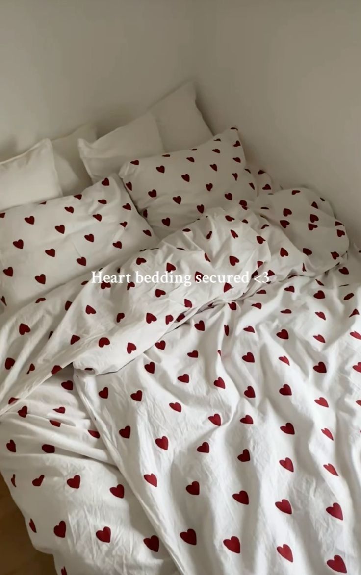 an unmade bed with red hearts on it