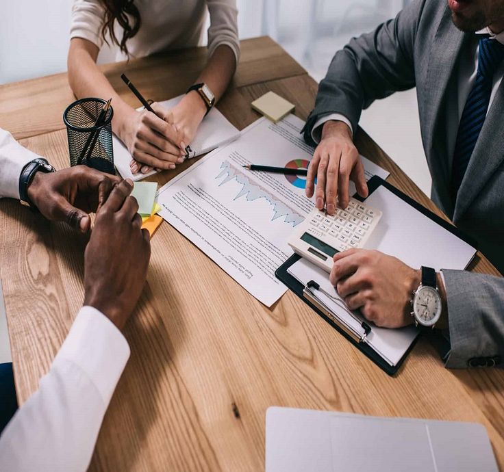 three people sitting at a table working on paperwork