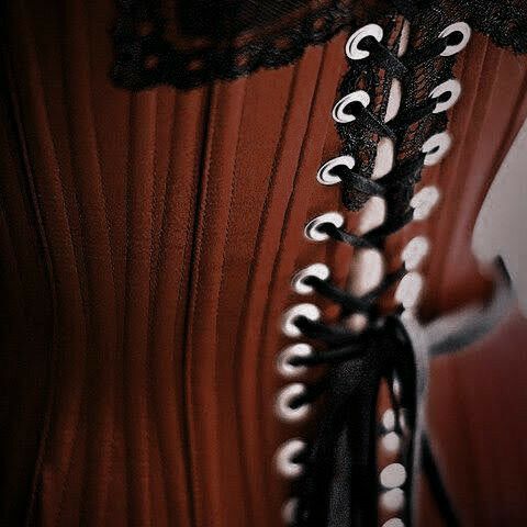 a corset with black and white lace on the top, attached to a red dress