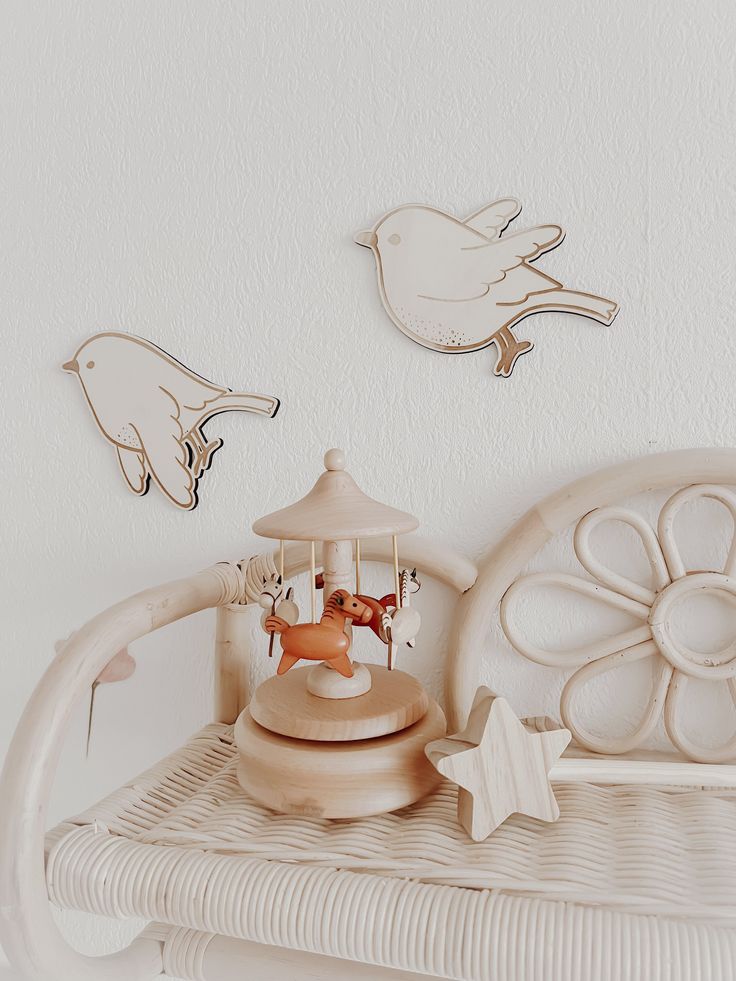 a white bed topped with a wooden carousel next to a wall mounted bird and dove