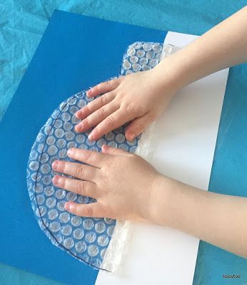 two hands touching each other on top of a piece of blue paper with white circles