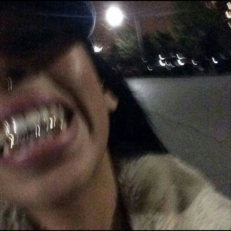 a person with braces on their teeth smiles at the camera while wearing a hat