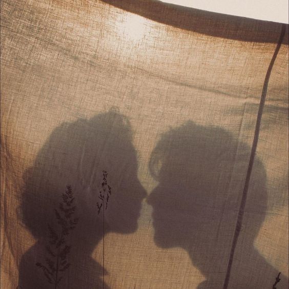 the shadow of two people's heads on a piece of cloth