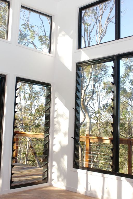 an empty room with three large windows overlooking trees