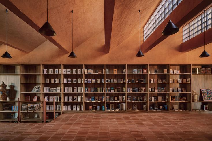 an empty library with many bookshelves and lights hanging from the ceiling above it