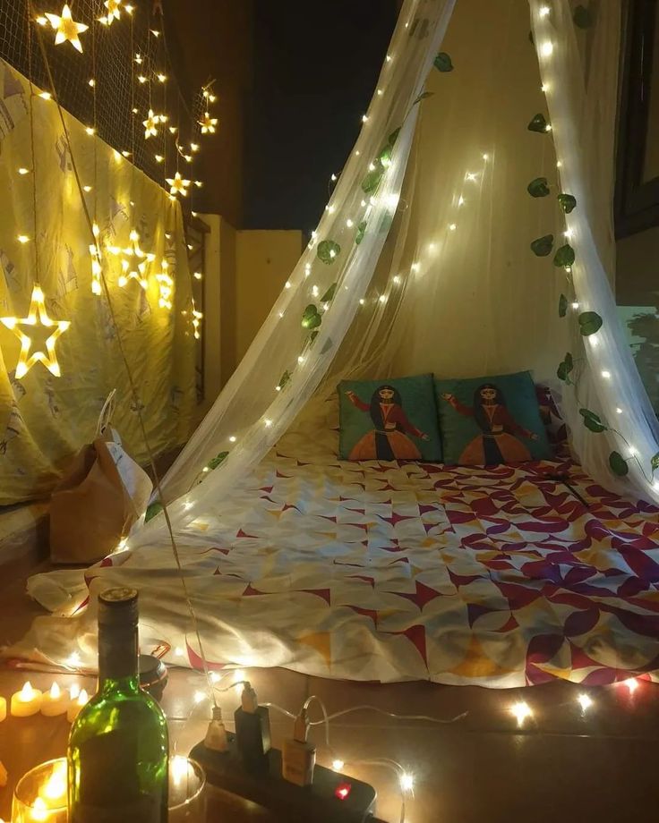 a bed covered in white netting with lights on the headboard and night time decorations