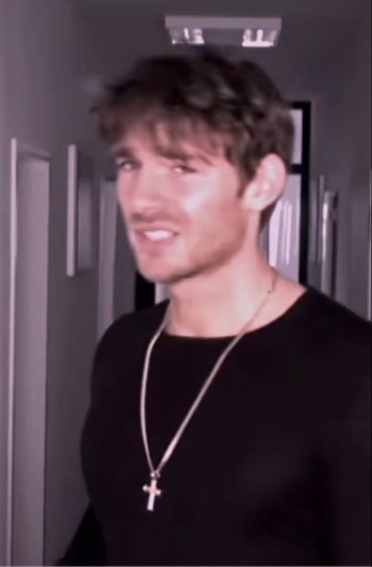 a young man wearing a black shirt and a cross necklace