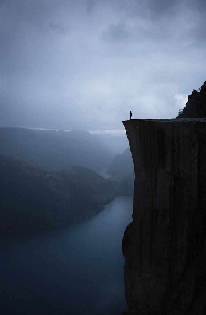 a person standing on the edge of a cliff overlooking a body of water at night