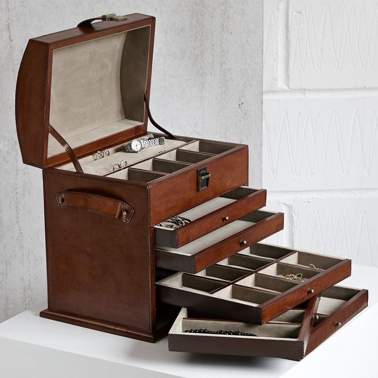 an open leather jewelry box sitting on top of a white table next to a brick wall