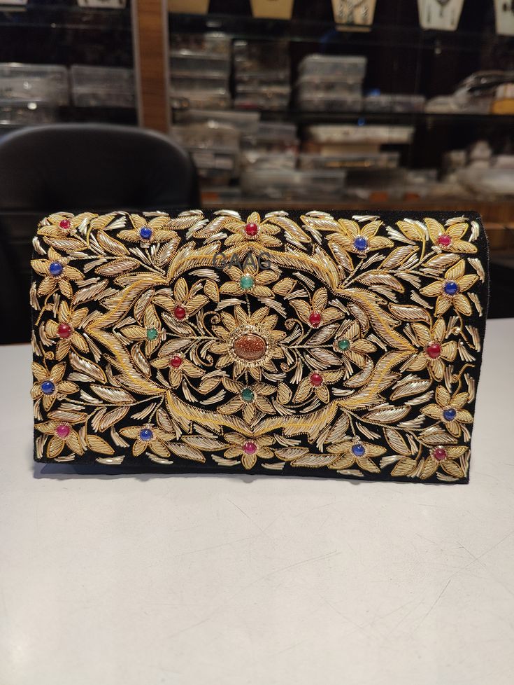 Beautiful hand-embroidered floral silk clutch bag inlaid with semi-precious stones. The front is completely covered in the design and has a closure flap with magnettic snap fastening. This clutch is perfect for daytime or night time. It is the ideal size for fitting all your essentials. It is a stylish accessory for each & every occasion. This equisite piece is even ideal for gifting to your near & dear one's . Thread - Silk Fabric - Velvet Variety of Semi-precious stones are used in this piece Elegant Rectangular Clutch With Intricate Embroidery, Festive Gold Hand-embellished Clutch, Luxury Elegant Clutch With Intricate Embroidery, Luxury Traditional Beaded Clutch, Vintage Gold Embroidered Clutch, Black Clutch Bags, Silk Clutch, Designer Leather Handbags, Velvet Clutch