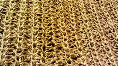 a close up view of a knitted blanket with brown and tan colors on it