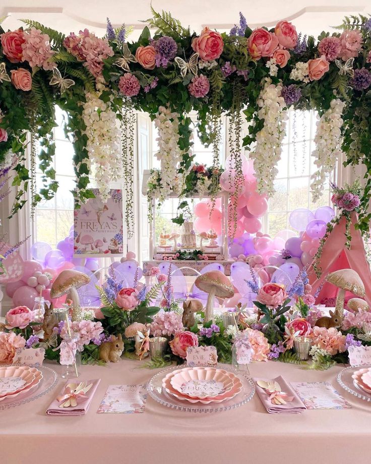 a table set up with pink and purple decorations