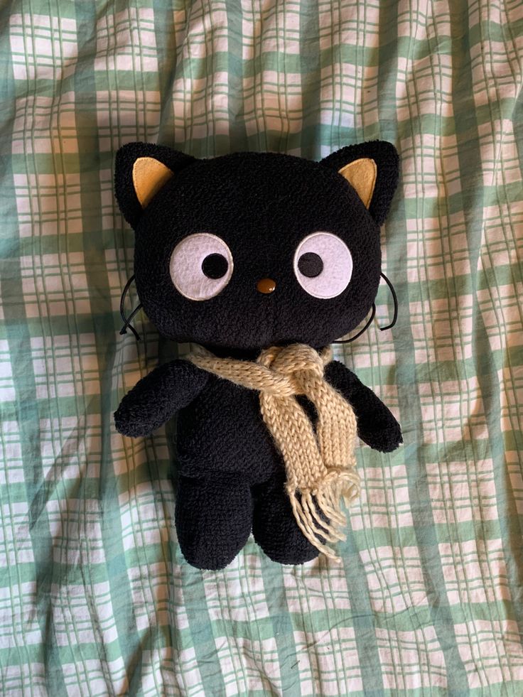 a black cat stuffed animal laying on top of a bed