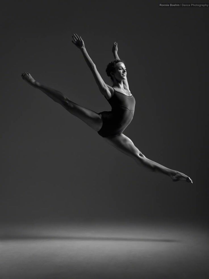 a woman in black leotard doing a ballet move with her legs spread out