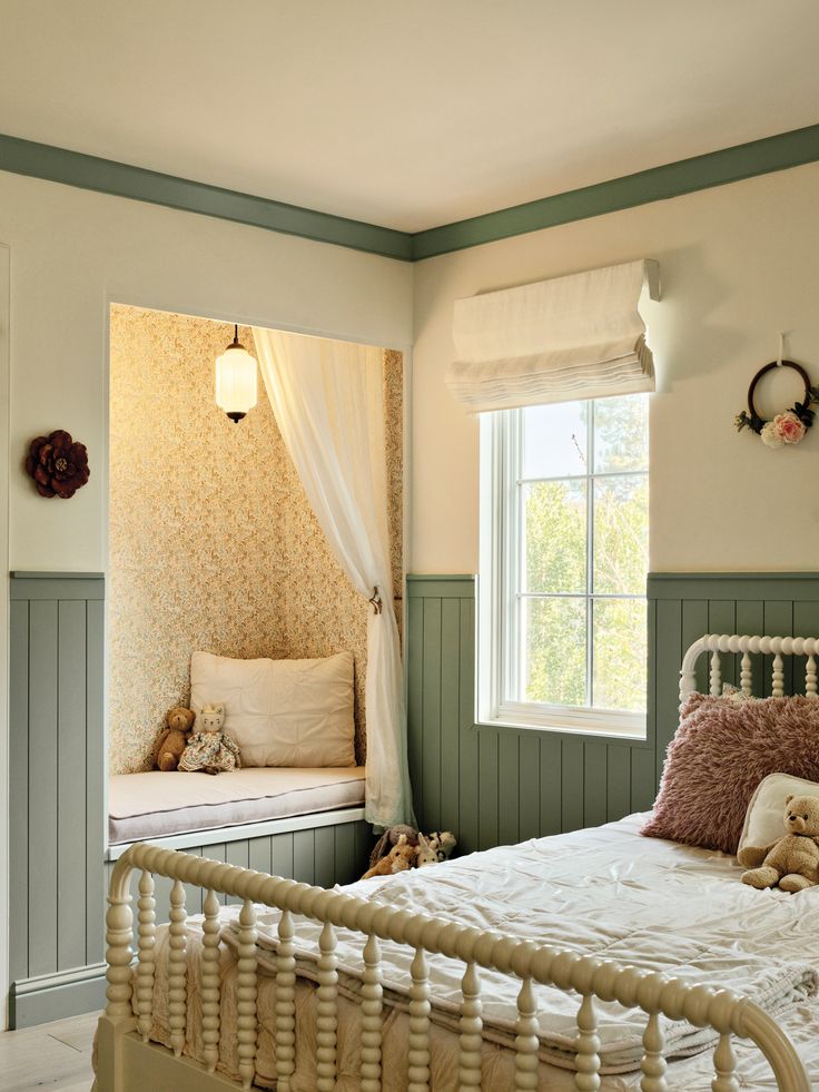 a white bed sitting in a bedroom next to a window with curtains on the windowsill