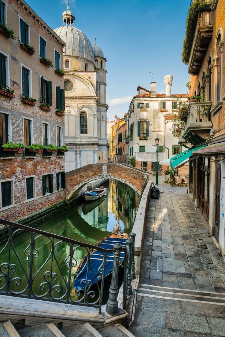 a narrow street with buildings and boats in the water next to stairs that lead up to them