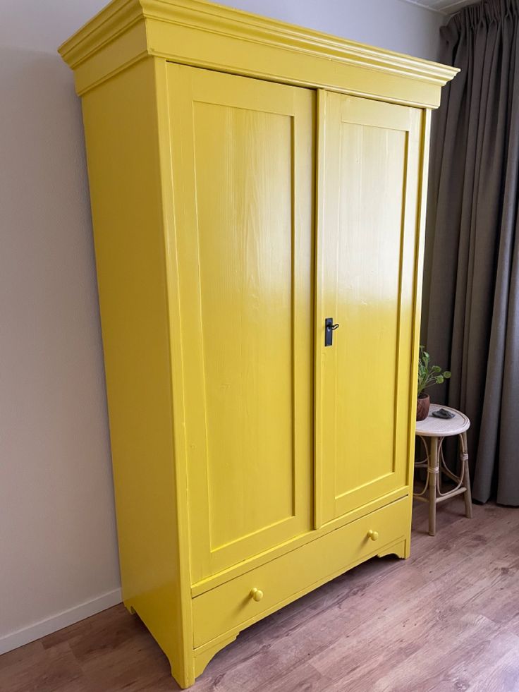 a yellow armoire in the corner of a room