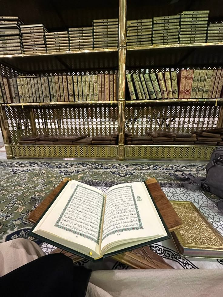 an open book sitting on top of a rug in front of a bookshelf