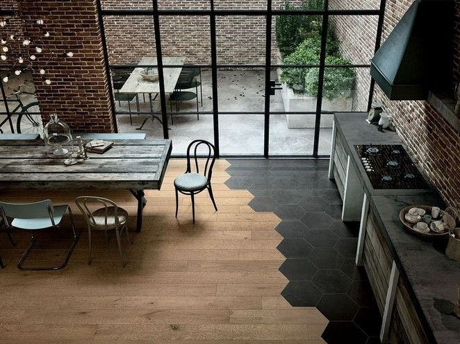 an open kitchen and dining area with wooden floors, brick walls, and large windows