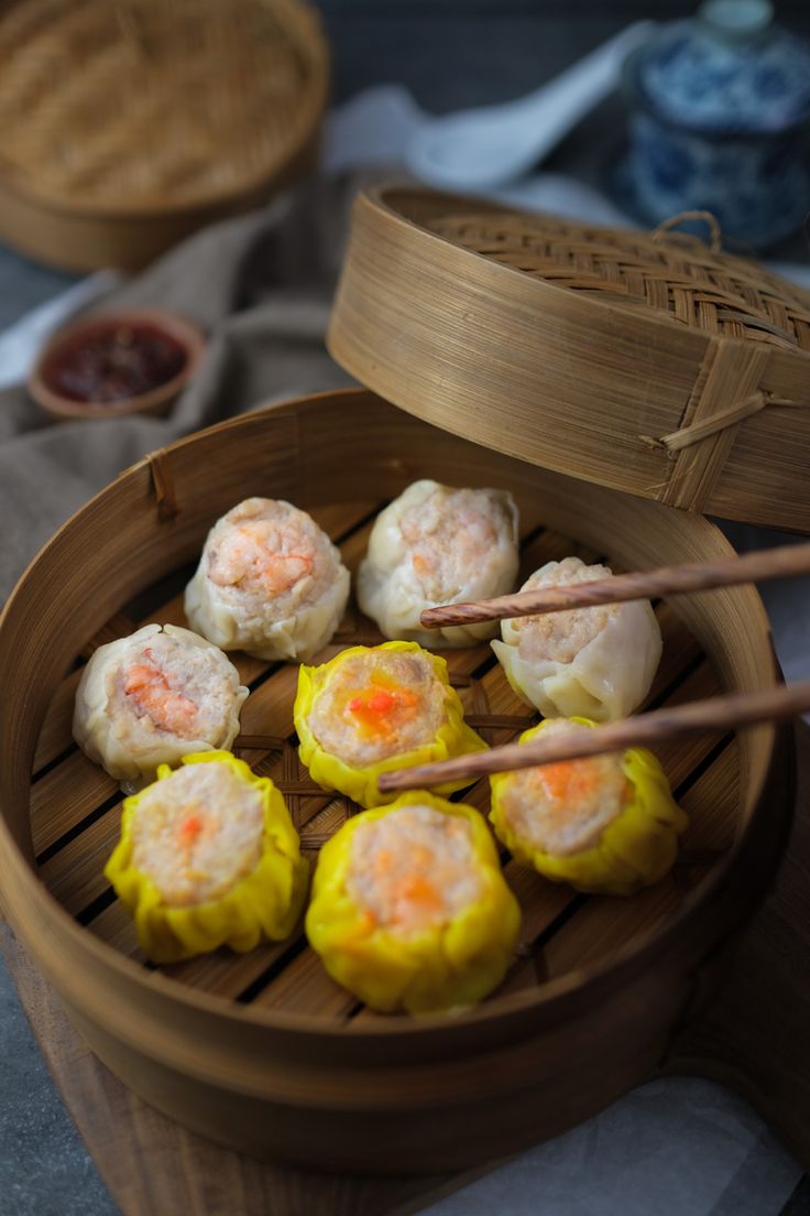 some food is in a wooden bowl with chopsticks