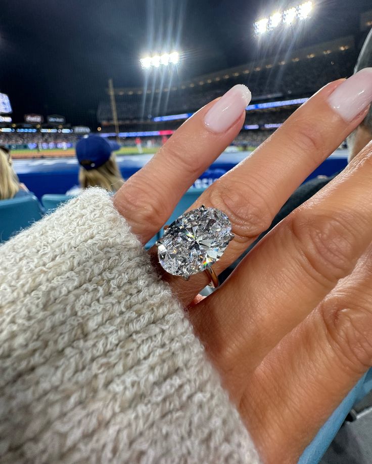 a close up of a person's hand with a diamond ring on their finger