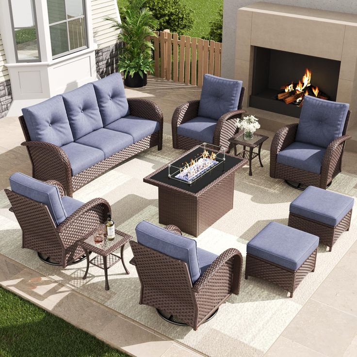 an outdoor living room with blue cushions and chairs around a fire place in the back yard