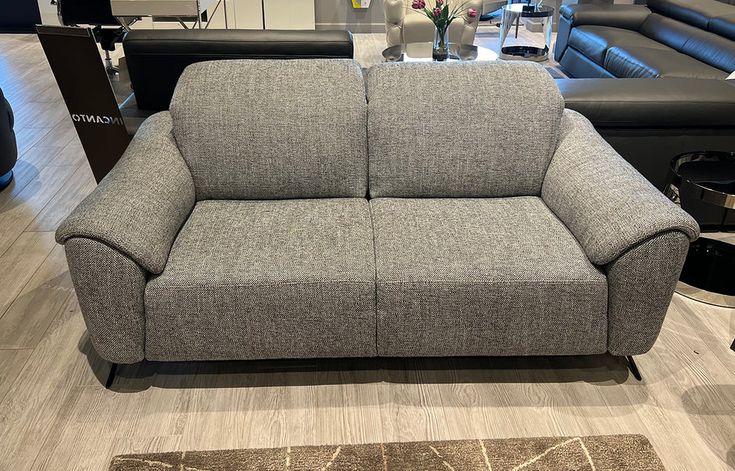 a gray couch sitting on top of a hard wood floor next to a black chair