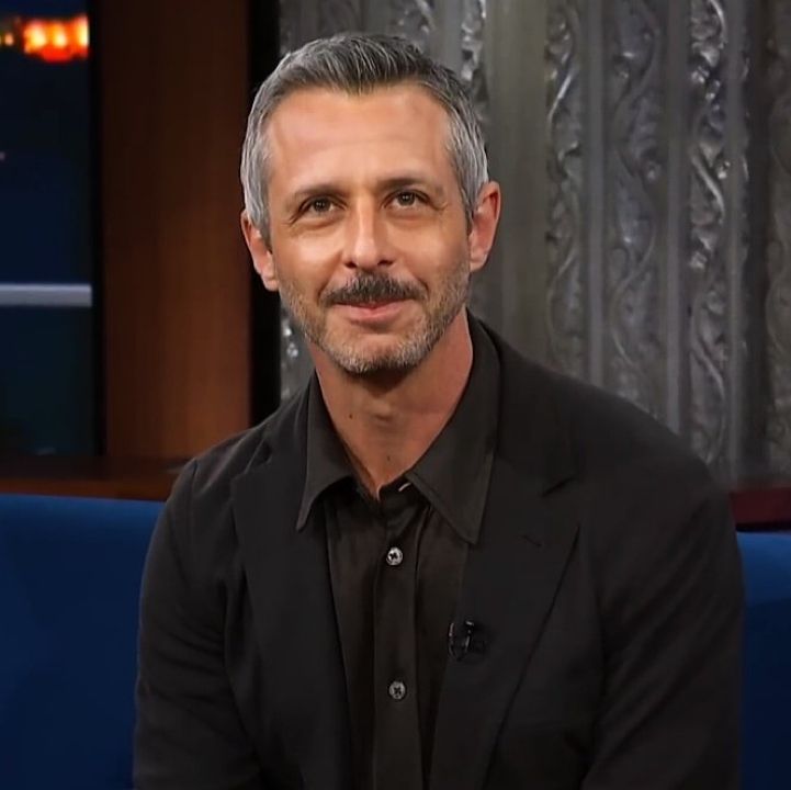 a man with grey hair sitting on a blue couch