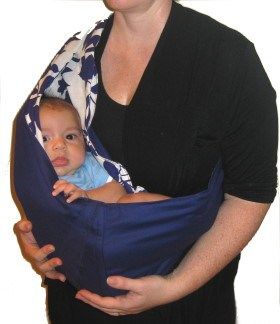 a woman is holding a baby in a sling