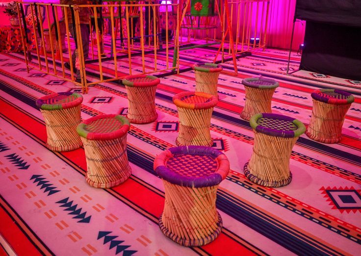 colorful baskets are lined up on the floor in front of a stage with pink lights