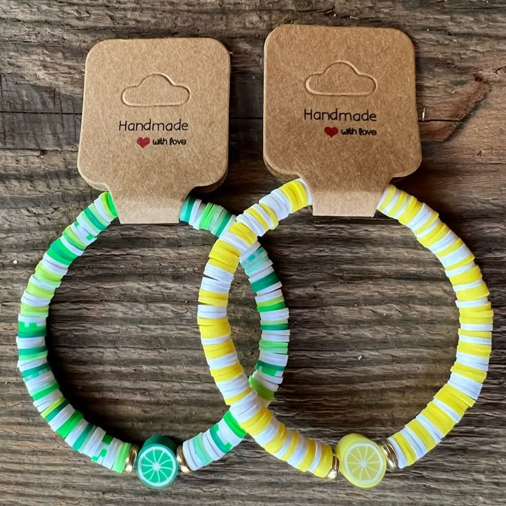 two bracelets with lemon slices on them sitting on top of a wooden table next to each other