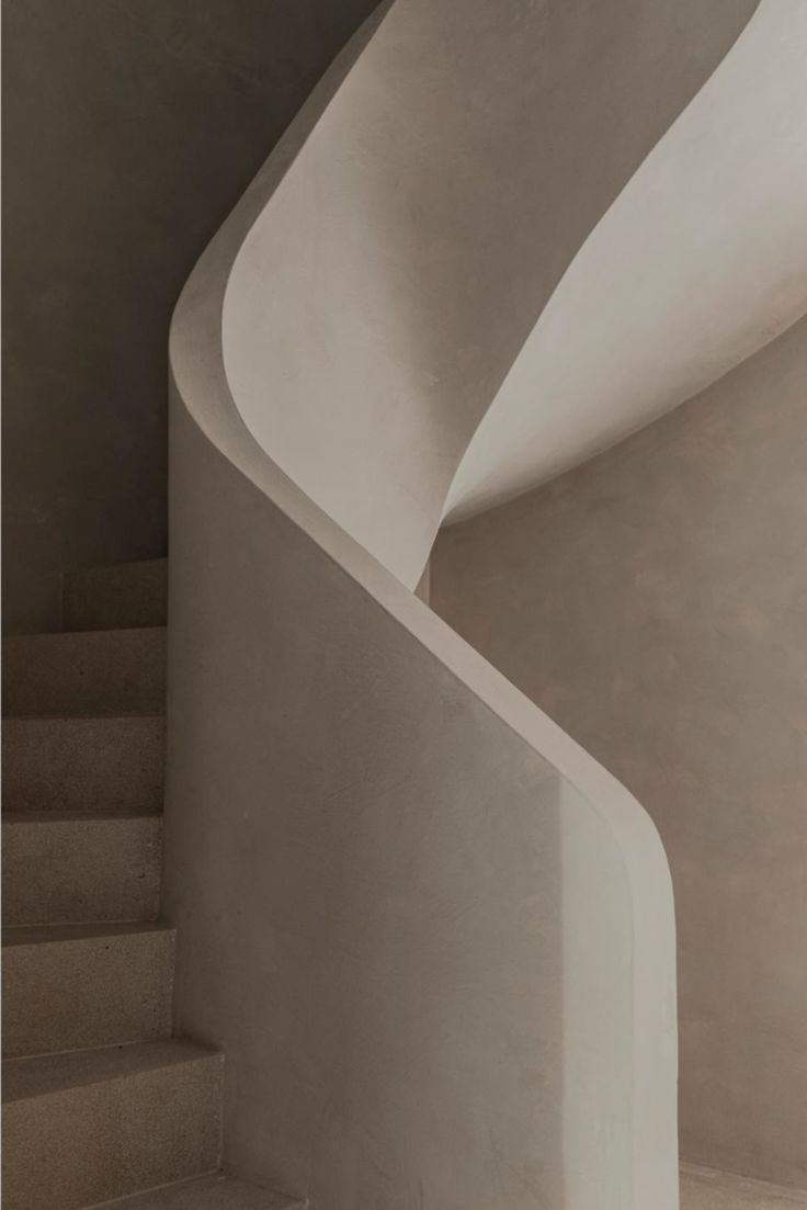 a white spiral staircase next to a wall