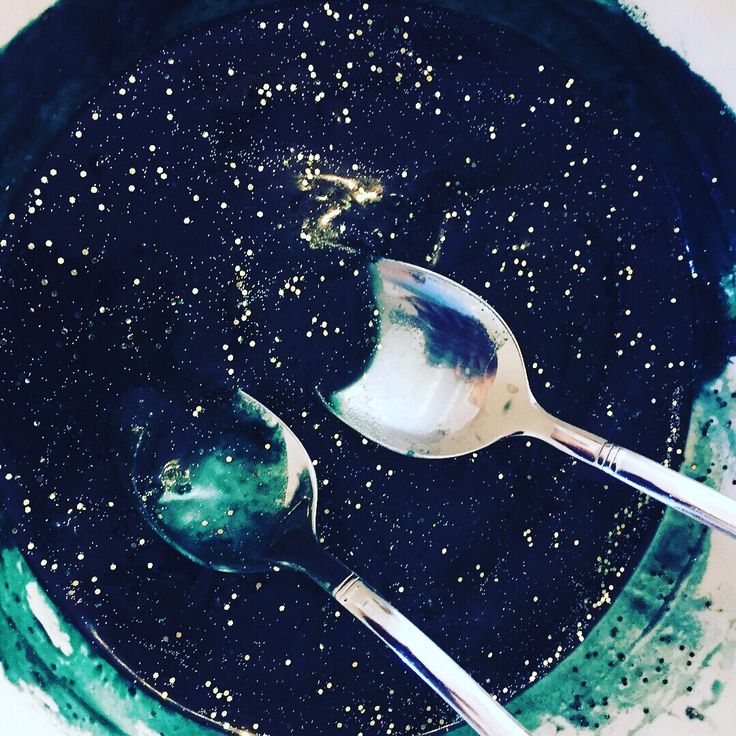 two spoons are sitting in a black bowl with blue and white speckles