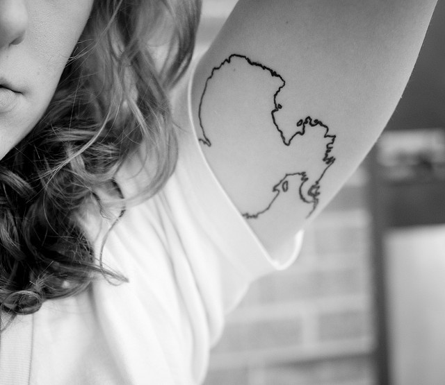 a woman holding her arm with a tattoo on it's left arm and shoulder