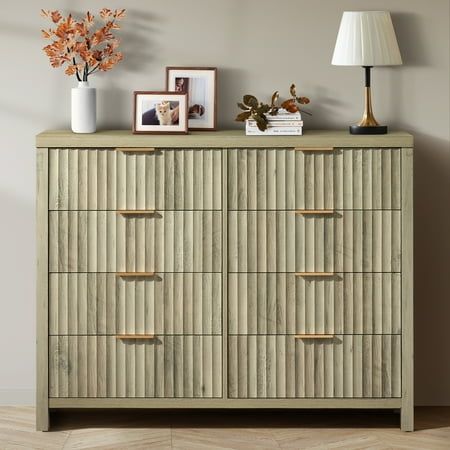 a dresser with several drawers and pictures on top, along with a lamp next to it