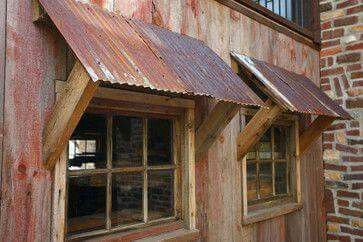 an old wooden building with a metal roof and window sill on the side of it