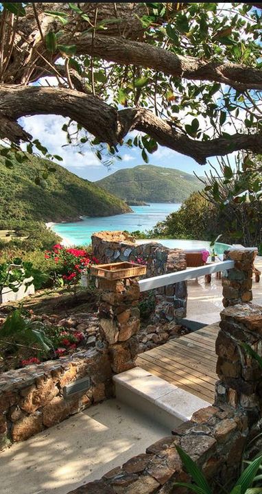 an outdoor patio with stone walls and steps leading to the water, surrounded by greenery