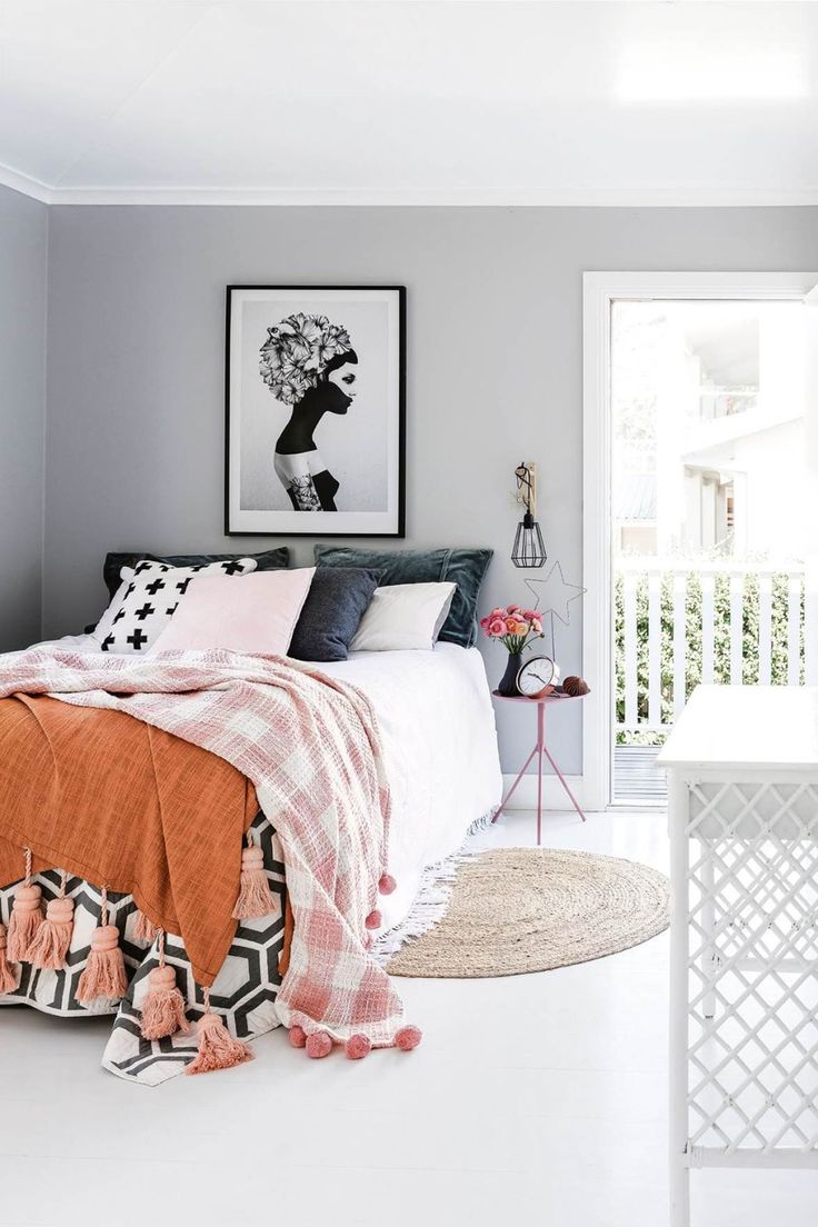 a bedroom with grey walls and white flooring is decorated in shades of pink, orange and black