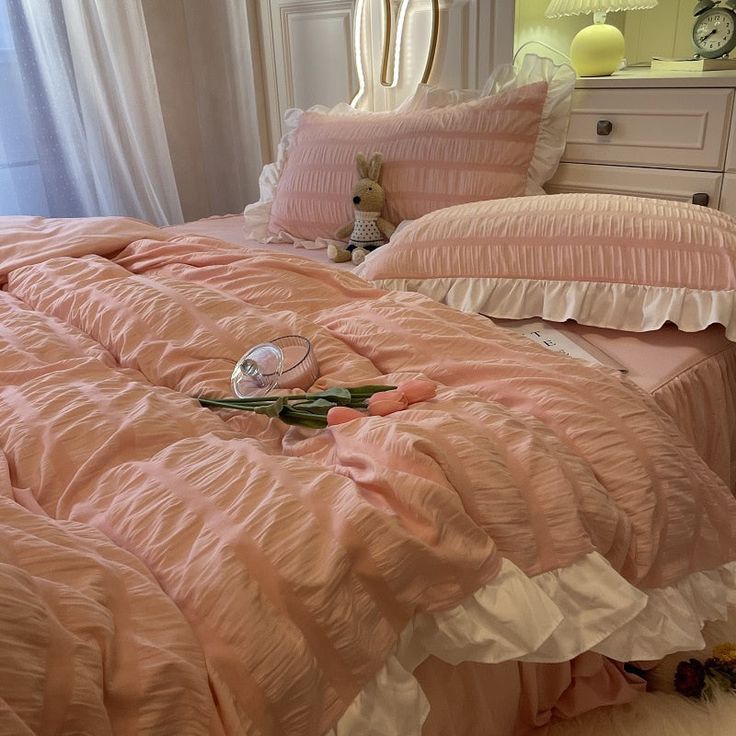 a pink bed with ruffled sheets and pillows